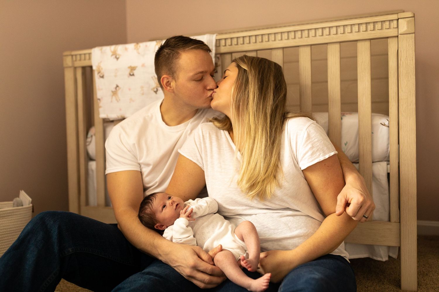 A nurturing scene in a nursery with a crib as a couple shares a moment with their newborn.