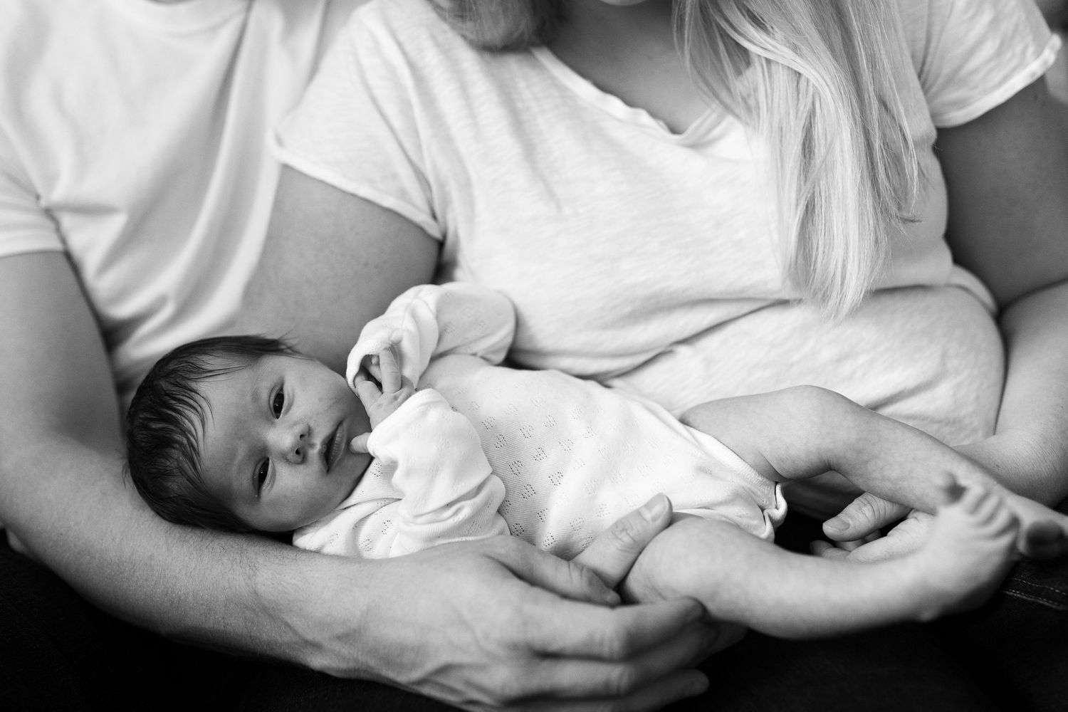 A black and white photo of a baby sleeping peacefully in white clothing.