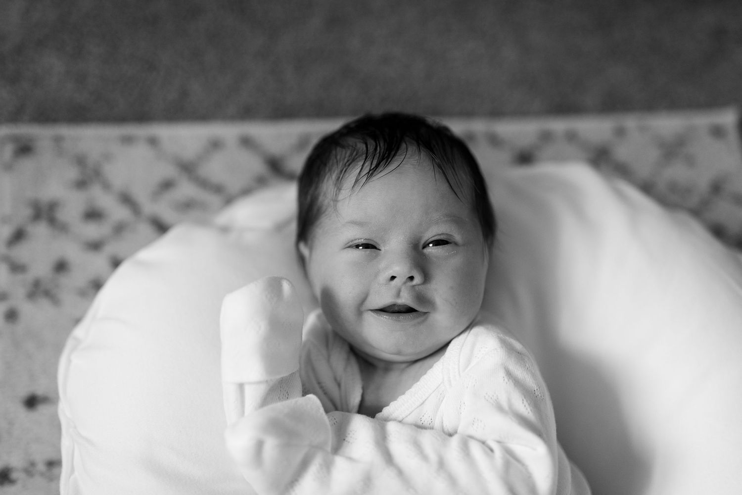 Black and white portrait of an infant sleeping peacefully on white bedding.