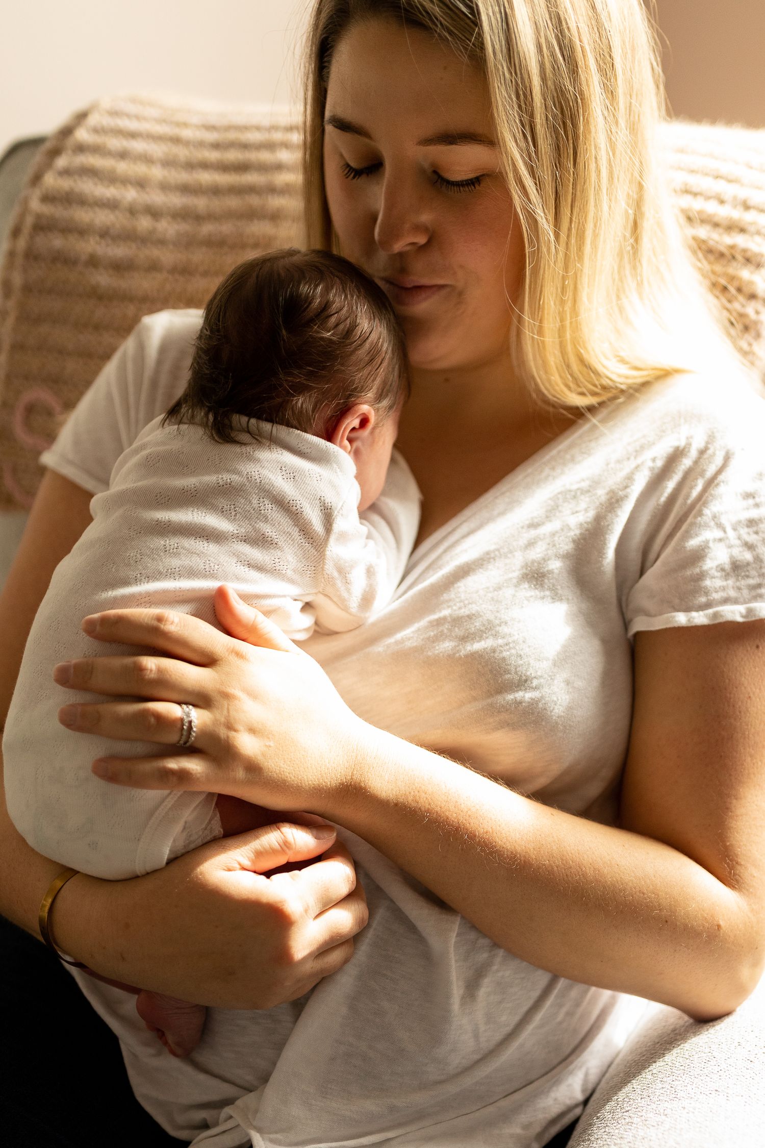 Mother in white shirt tenderly holding and bonding with newborn baby in intimate moments.