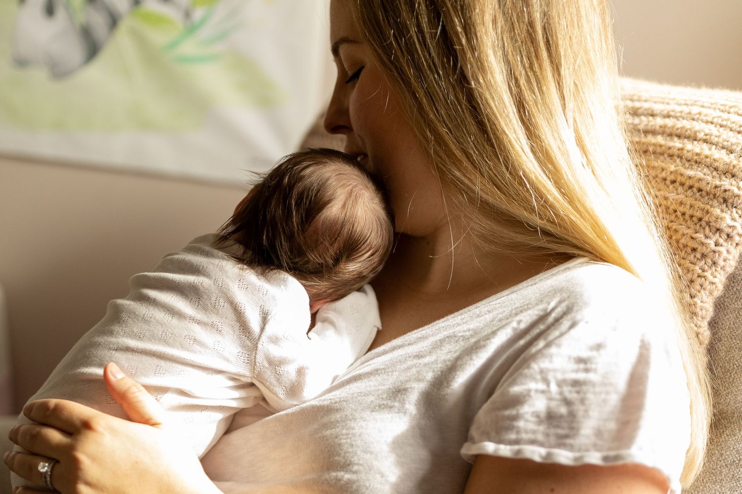 Mother in white shirt holding baby in soft natural lighting creating intimate moments.