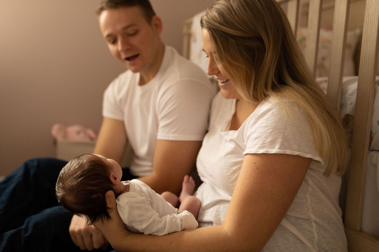 An intimate family moment in a softly lit room as they bond with their newborn baby.