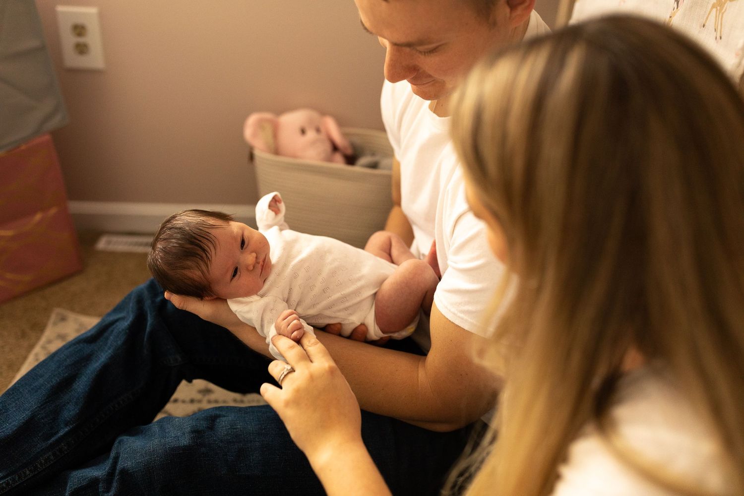 A tender moment of caring for a small infant on blue fabric in a warm-lit room.