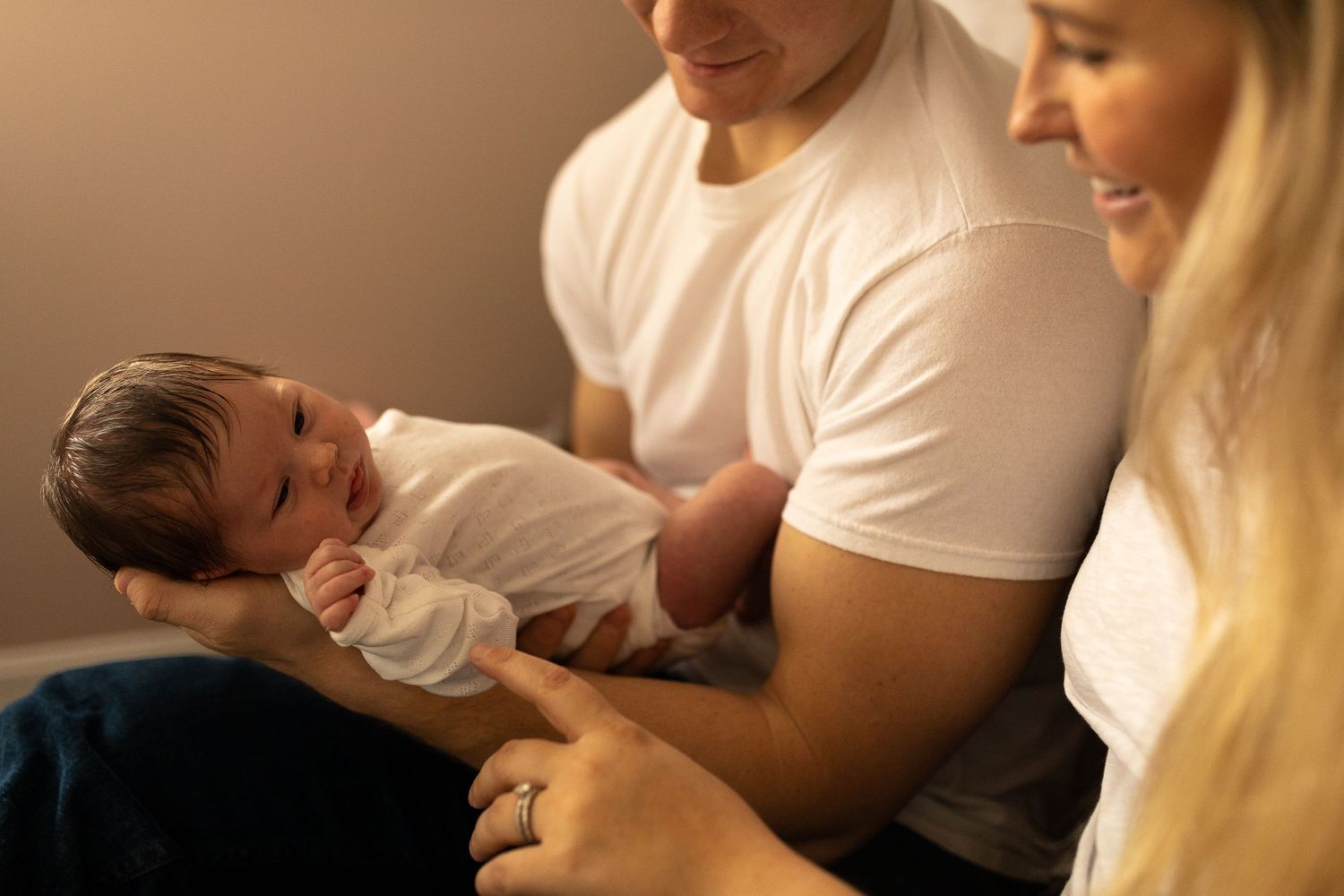 A gentle moment with a newborn baby being cradled in warm lighting.