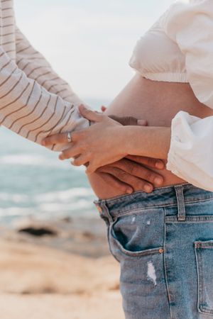 Close-up shots of hands embracing against ocean backdrop.