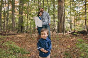 Little boy upfront and unsure of photographer while Mom and Dad cuddle behind him