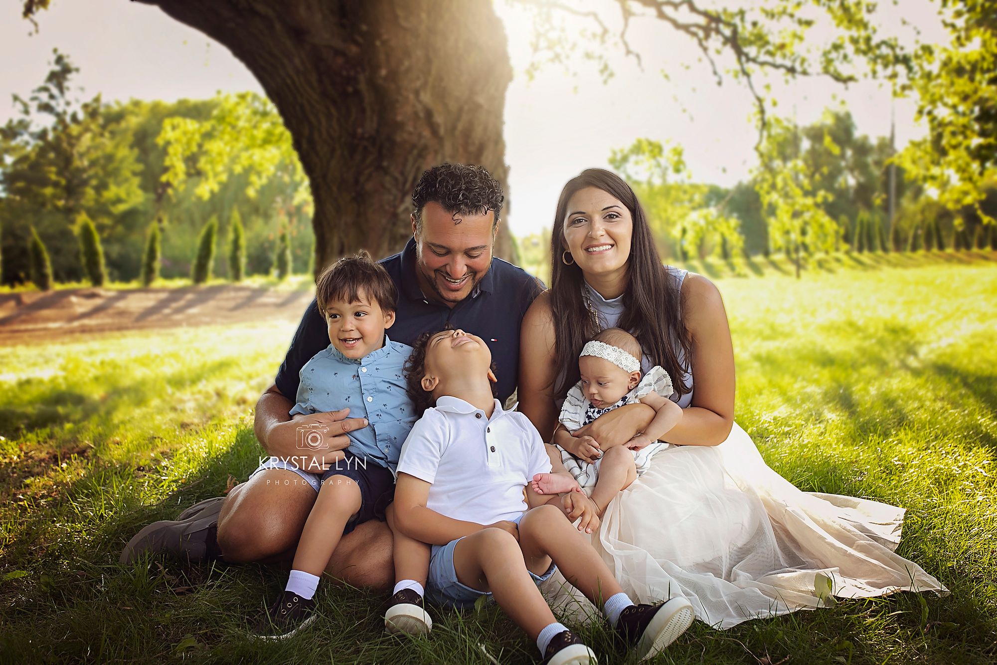 Dressed up family pose on their property with trees behind in which they planted themselves