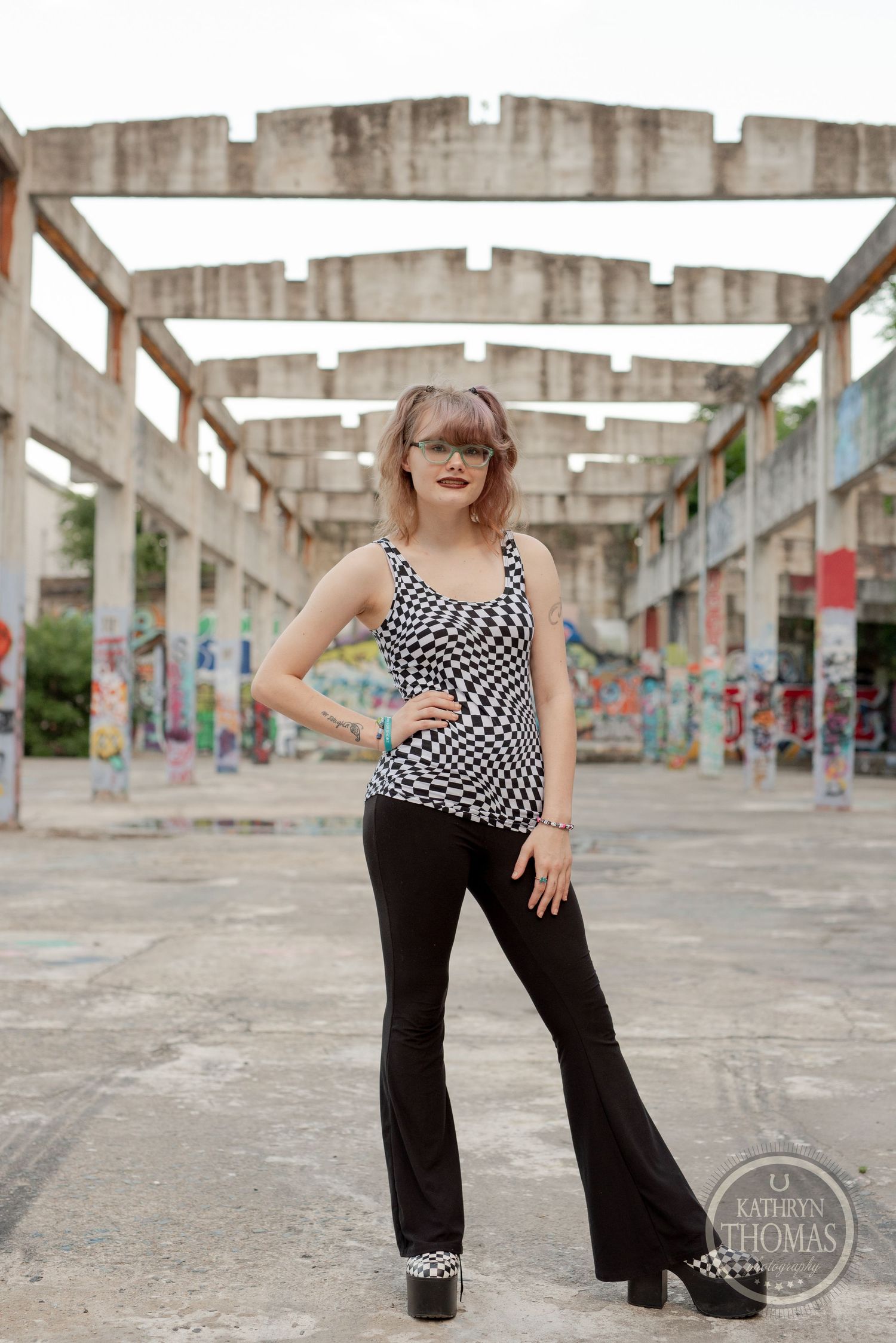 A retro-inspired fashion shoot in an urban setting with checkered tank top and flared pants against graffiti walls.