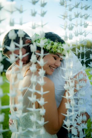 Bride leaning on grooms shoulder looking through 1000 cranes