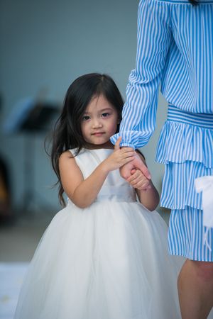 Shy flower girl holding mom's hand