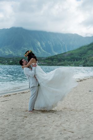 Groom holding up bride on a beach