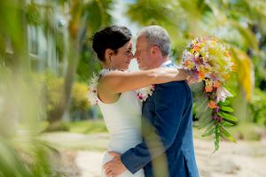 Bride and groom hugging with palm trees all around them