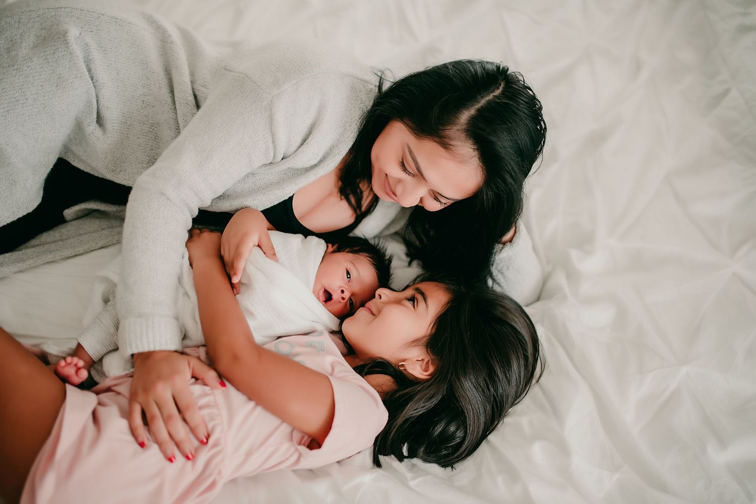 A tender moment shared between parent and child lying on white bedding.