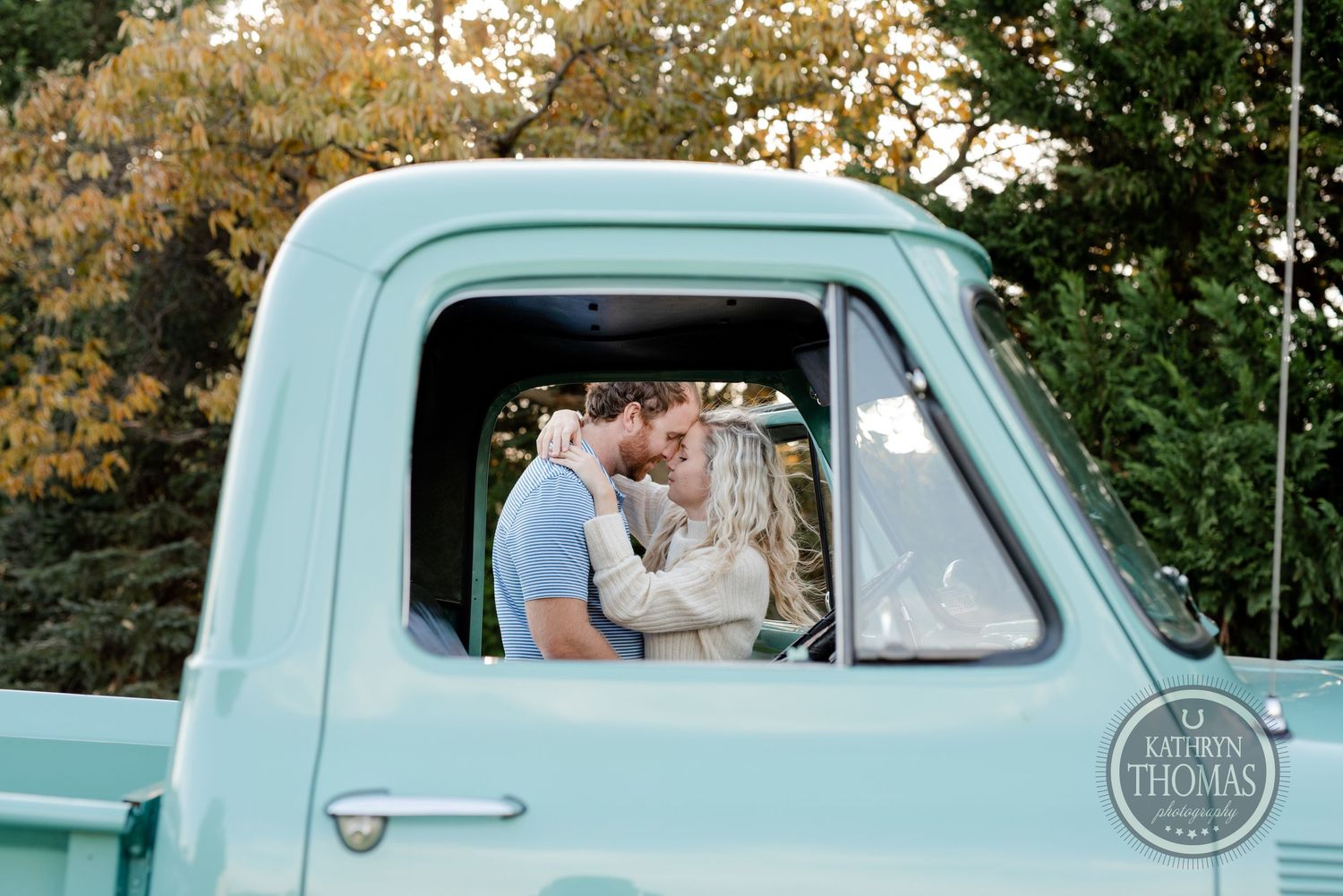 Romantic couple sharing a tender moment inside a vintage mint green truck.