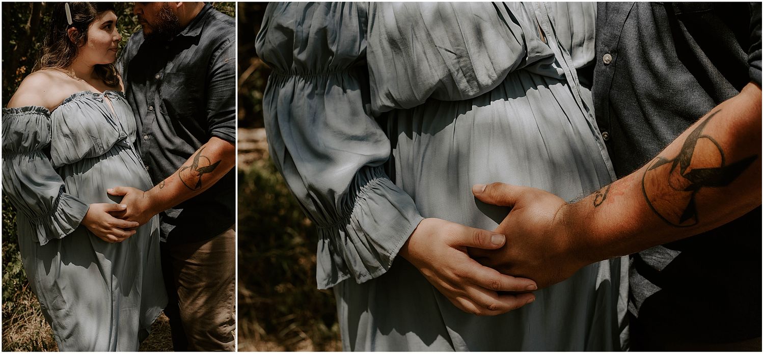 Close-up details of hands tenderly cradling a pregnant belly in a light blue dress.