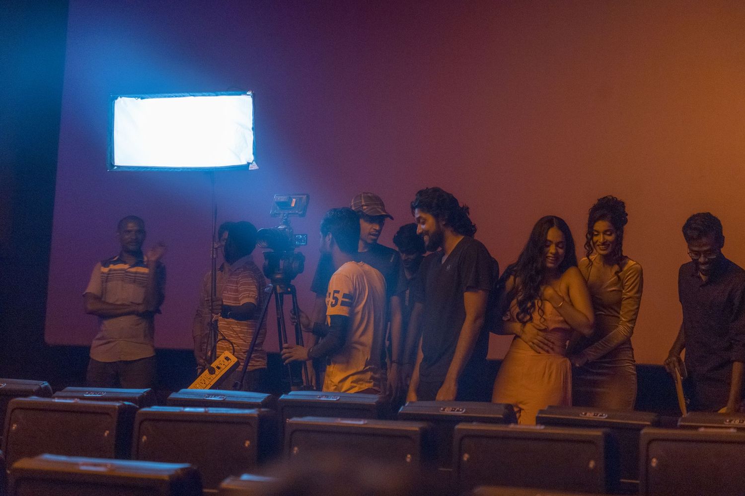 Group of people standing in a dark room with blue and orange lighting effects.