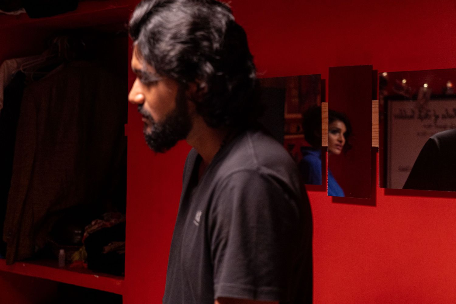 Side profile shot of someone against a red wall in dramatic lighting.