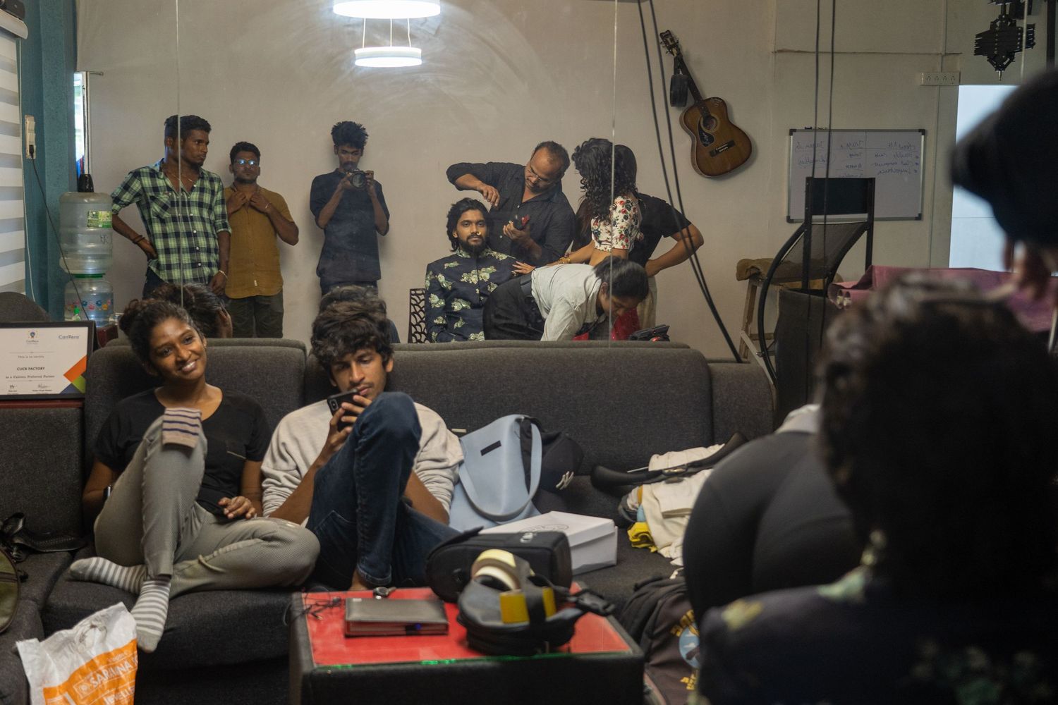 Behind the scenes shot of a music or recording studio with instruments and people relaxing.