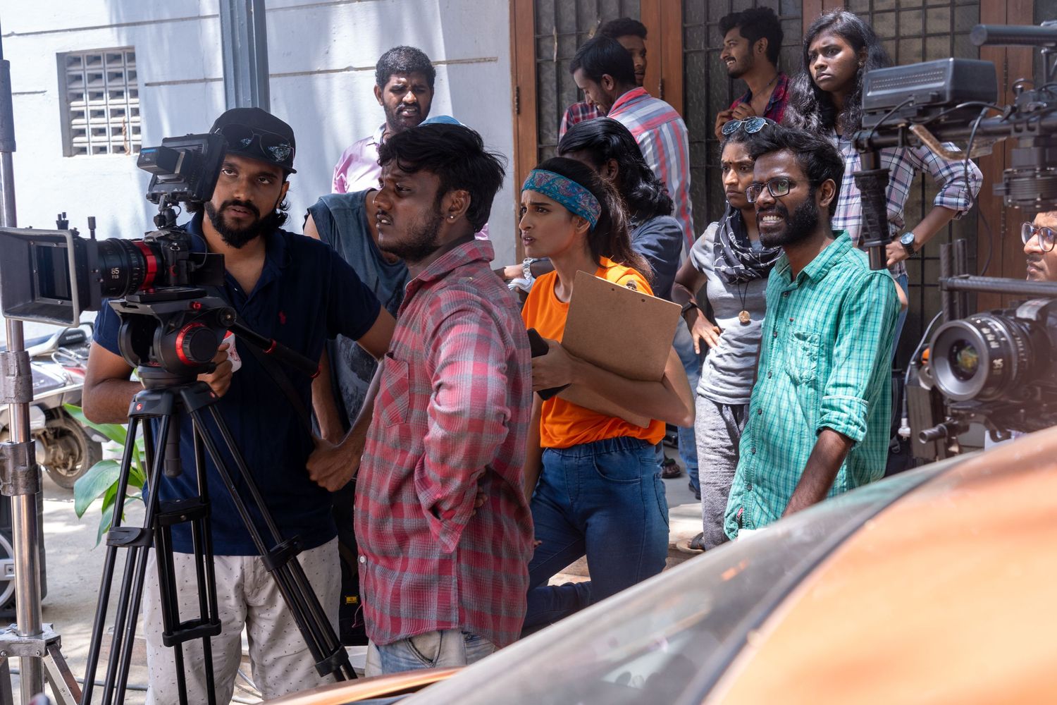 Film crew with cameras and equipment working together on an outdoor production shoot.