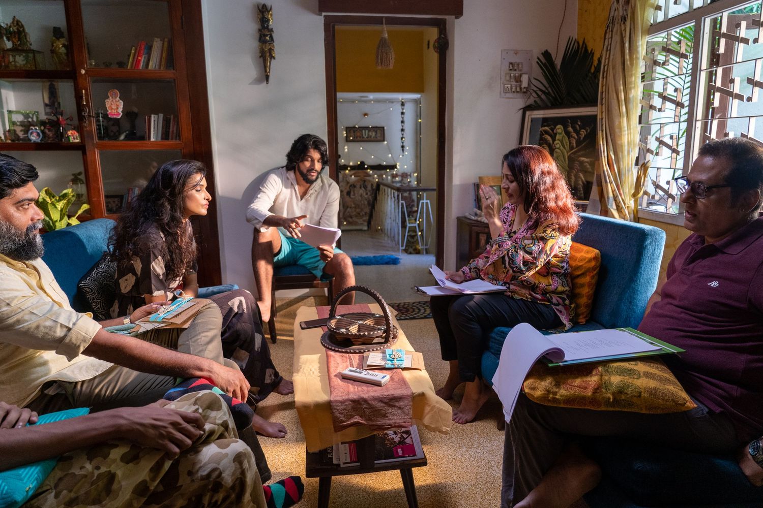 A group sits together in a cozy living room during what appears to be a creative meeting or discussion.