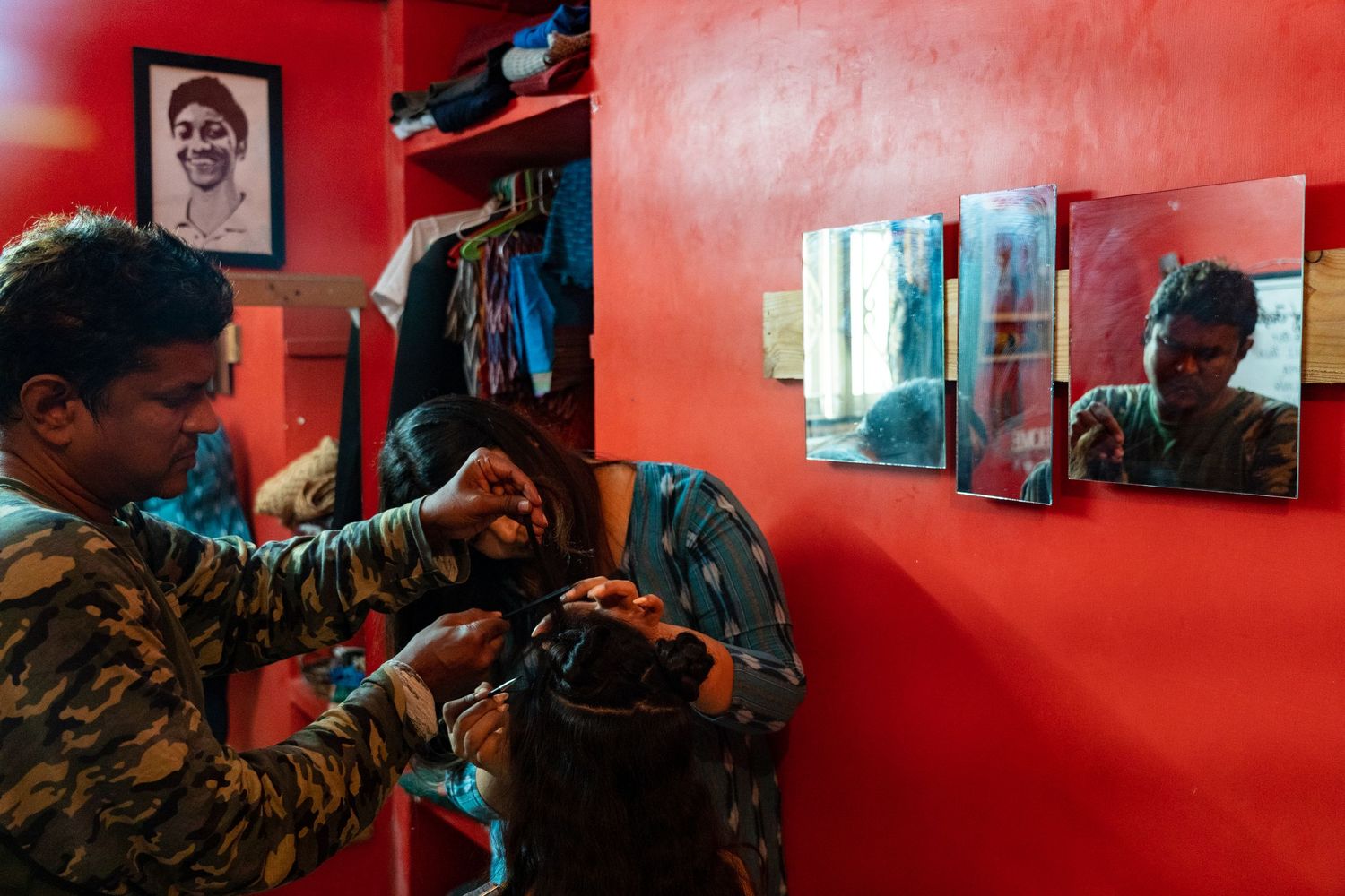 Camera operator adjusts equipment against a vibrant red wall during a film production.