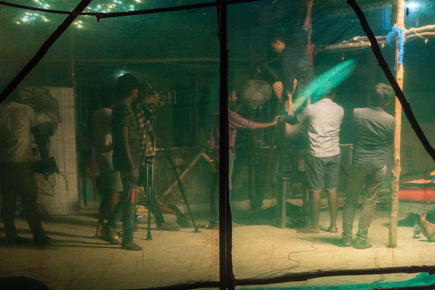 Dark silhouettes of people visible through tent fabric with atmospheric lighting.