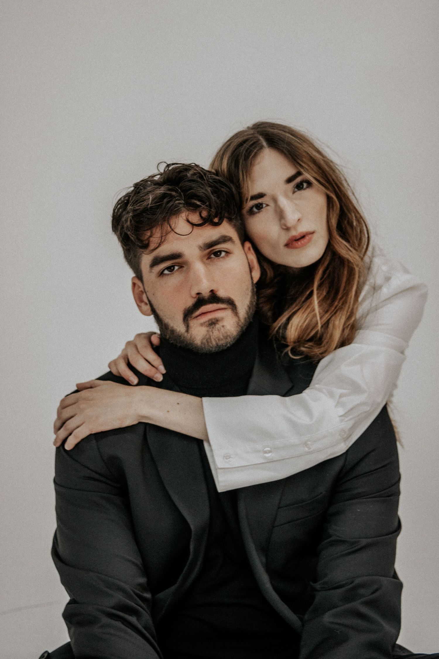 Artistic portrait of a couple embracing against white background in monochromatic style.