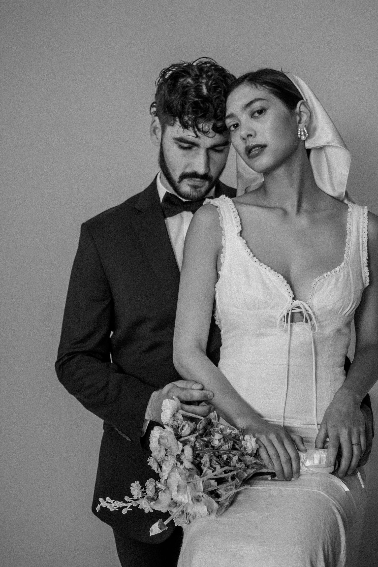 Vintage-style black and white wedding portrait with floral bouquet.