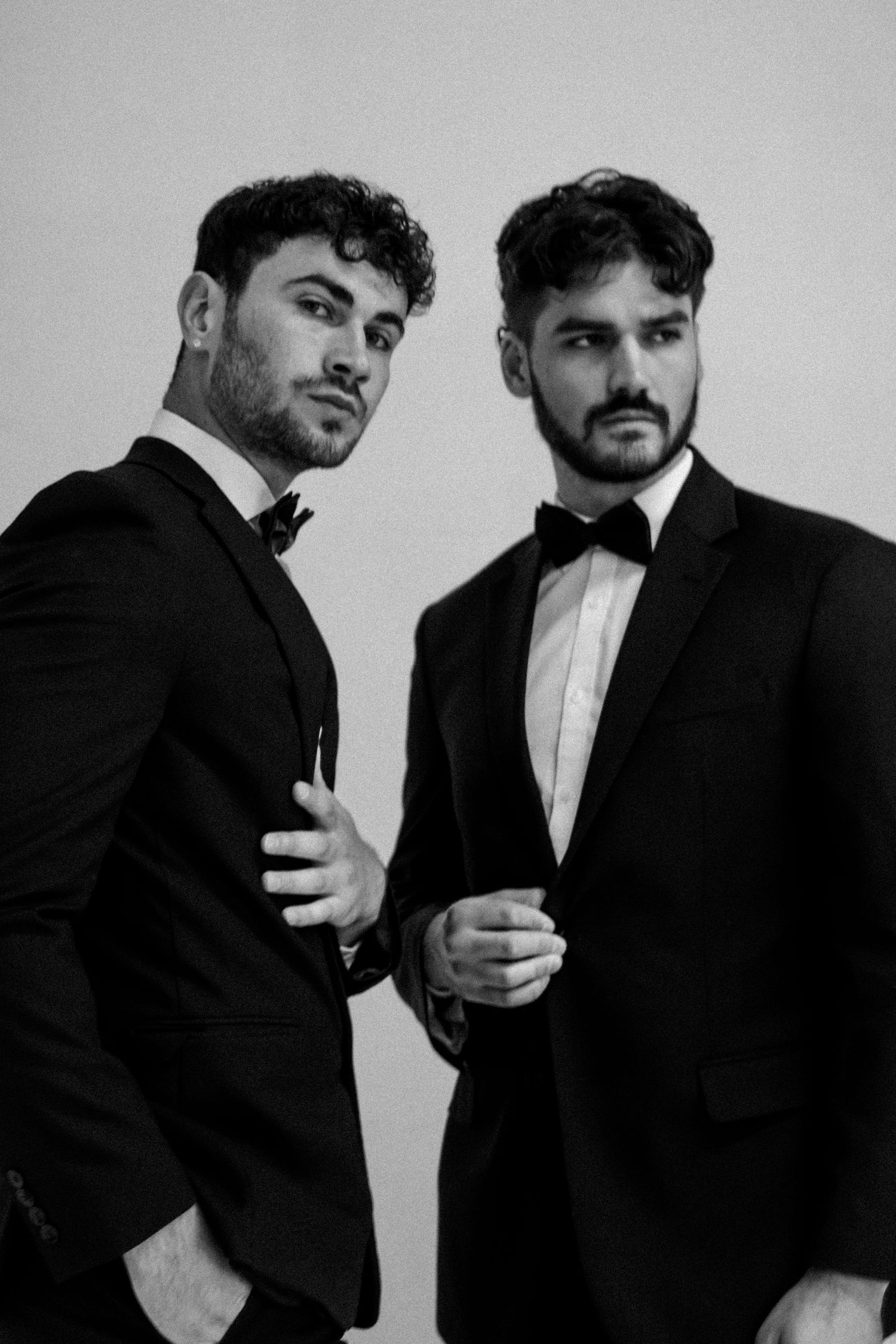 Black and white portrait of two men in formal tuxedos and bow ties.