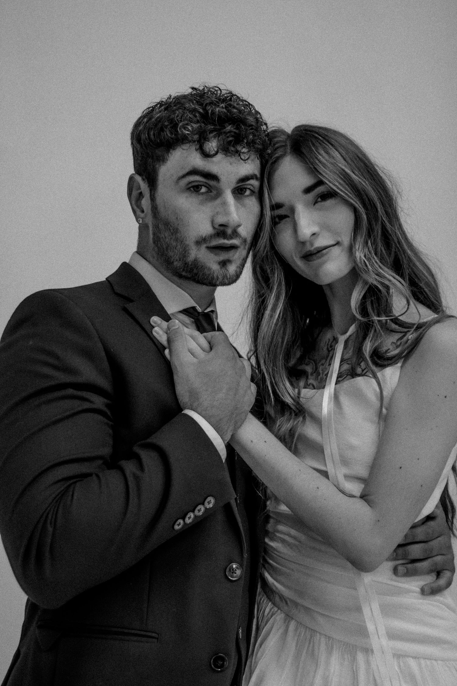 Black and white romantic portrait of a couple in formal wedding attire.
