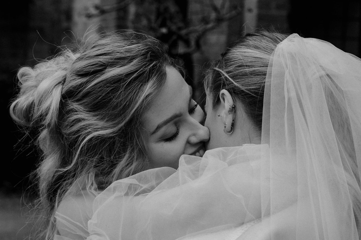 An intimate black and white wedding photo showing two people sharing a tender moment with a bridal veil.