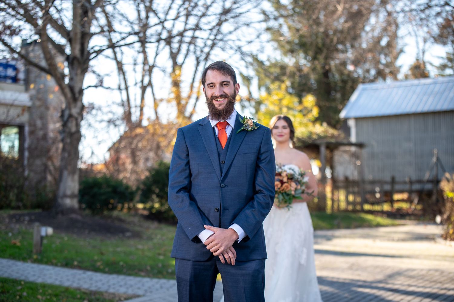 Wedding first look moment in a rustic outdoor setting with autumn trees in the background.