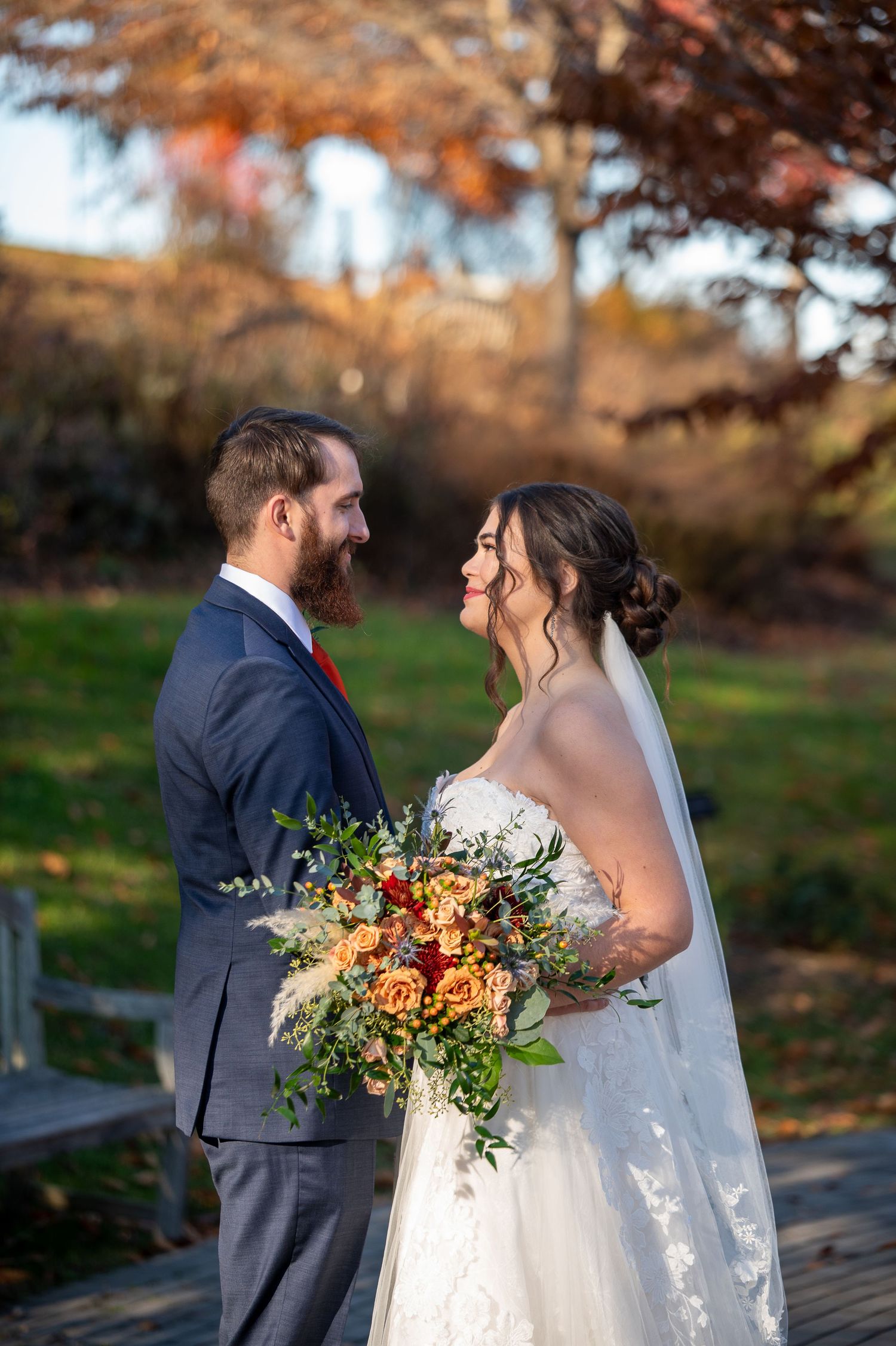 Couple shares joyful moment during fall wedding with vibrant autumn bouquet.