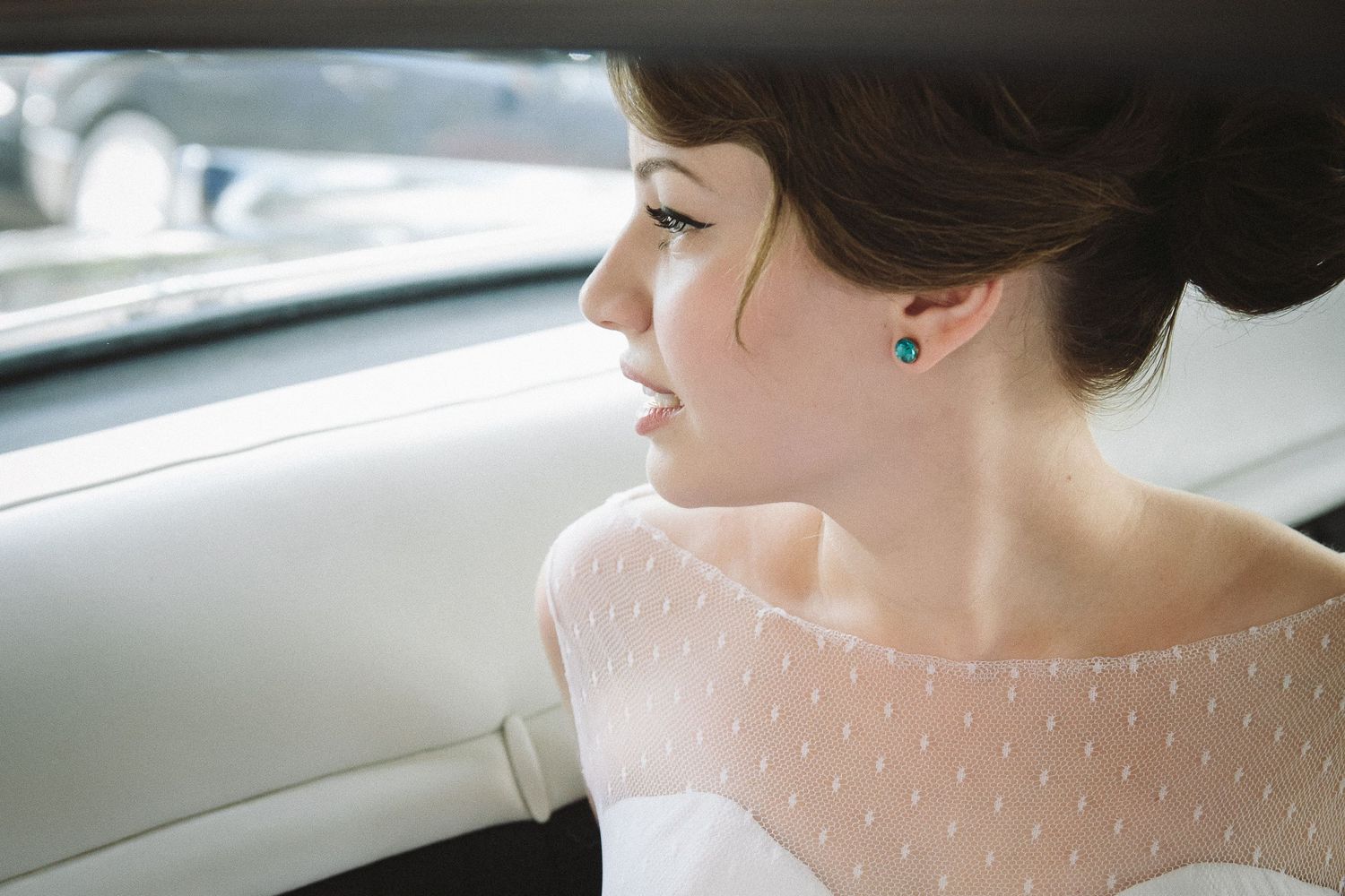 Side profile view of someone in white dotted dress sitting in vintage car.