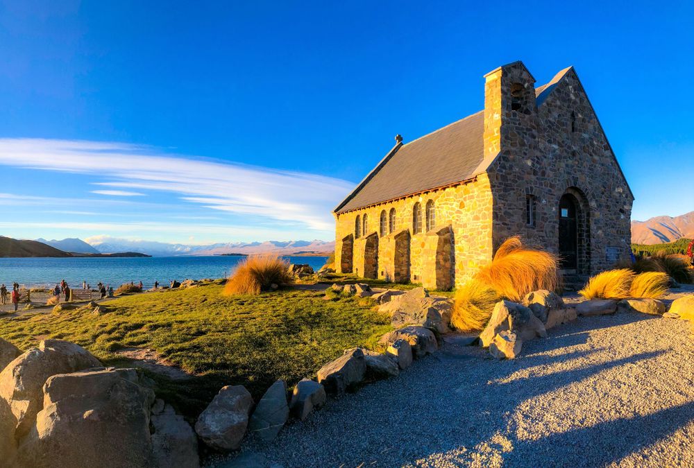 Stone church building photographed at golden hour in mountainous landscape.