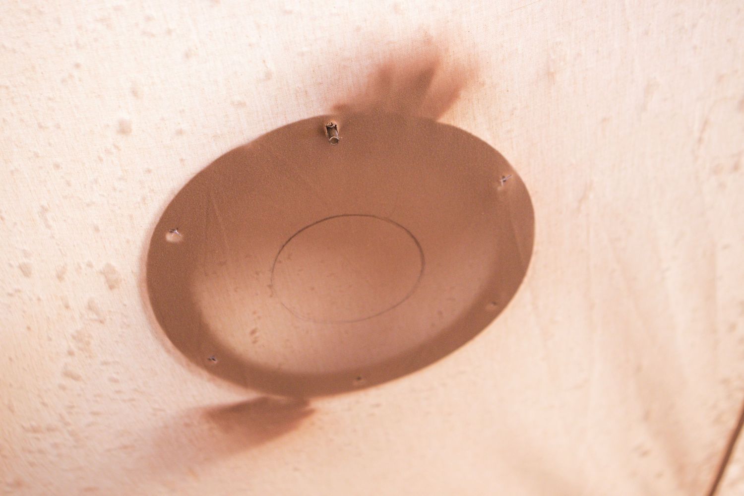 Close-up of round metal flange mounted on white surface.