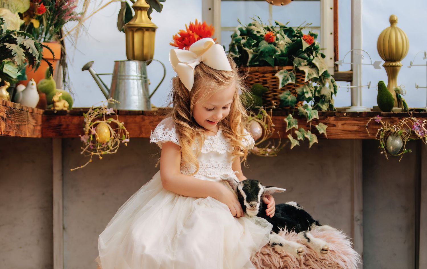 girl in dress holding baby goat in greenhouse