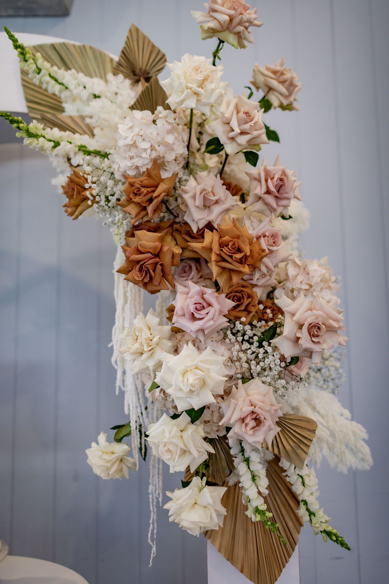 Stunning dried floral arrangement featuring roses and palm leaves in neutral tones.