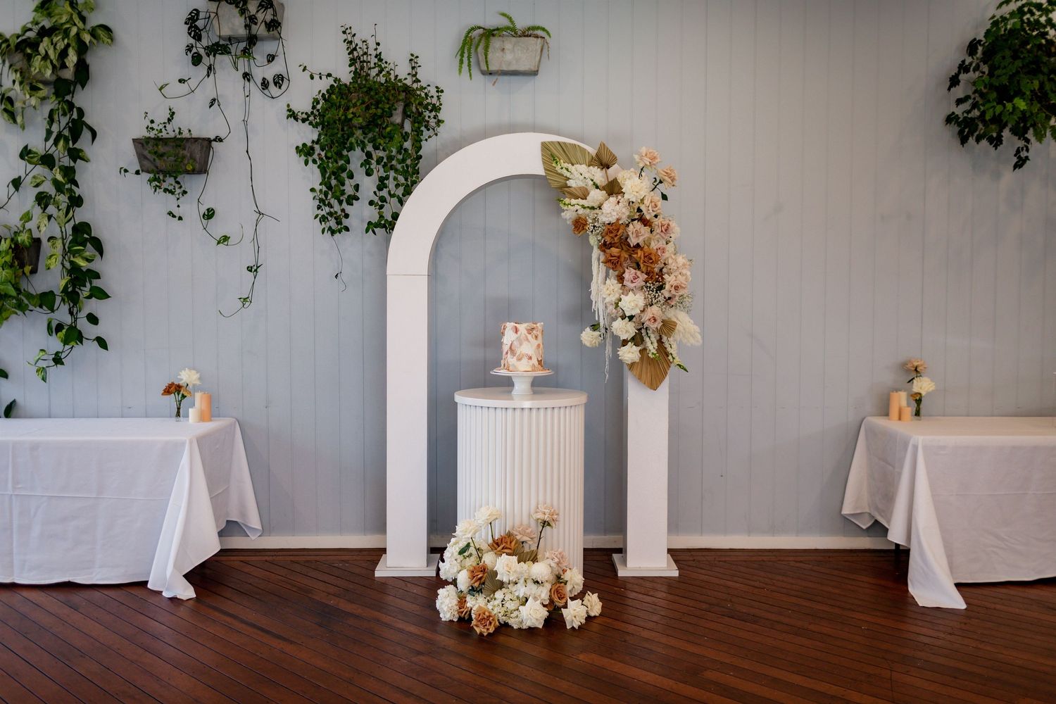 Wedding ceremony arch decorated with dried flowers and white fabric in an indoor setting.
