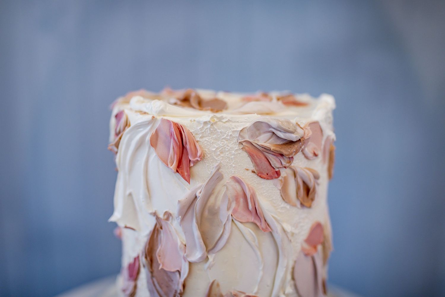 Close-up shot of a textured cream-colored cake with delicate peach-toned floral decorations.