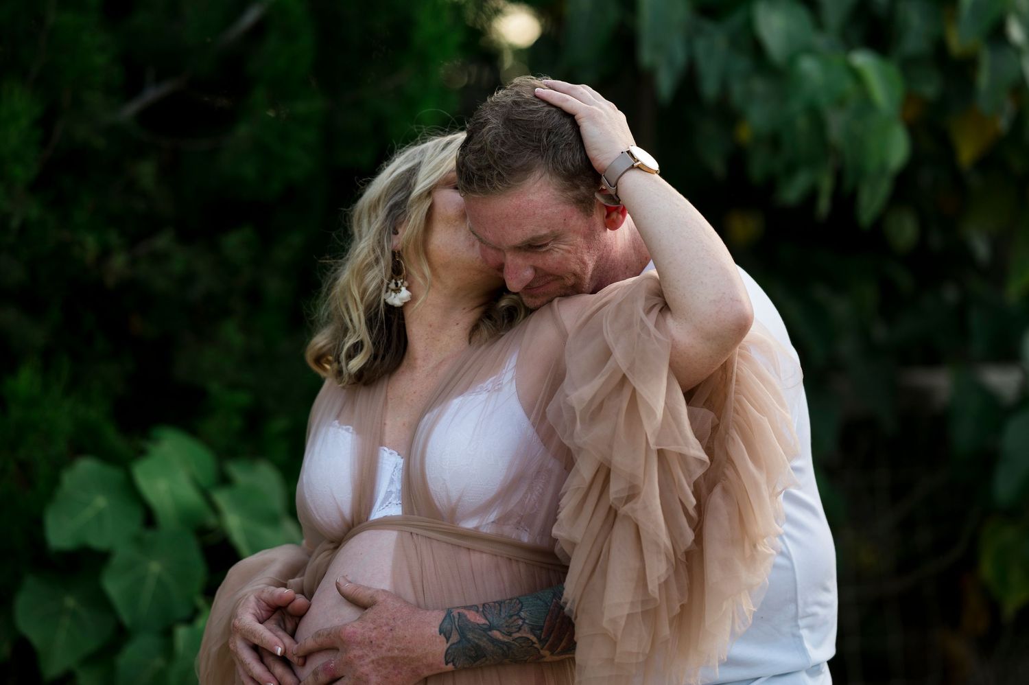 An intimate maternity moment captured outdoors with soft natural lighting.