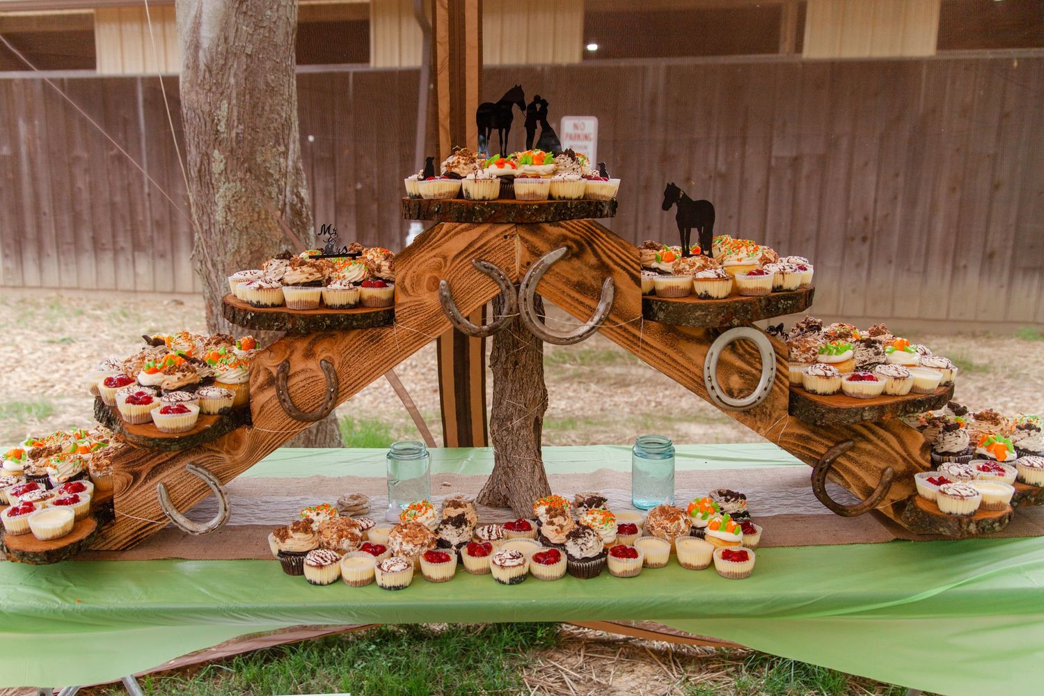 Rustic wooden cupcake display stand with multiple tiers at wedding reception.