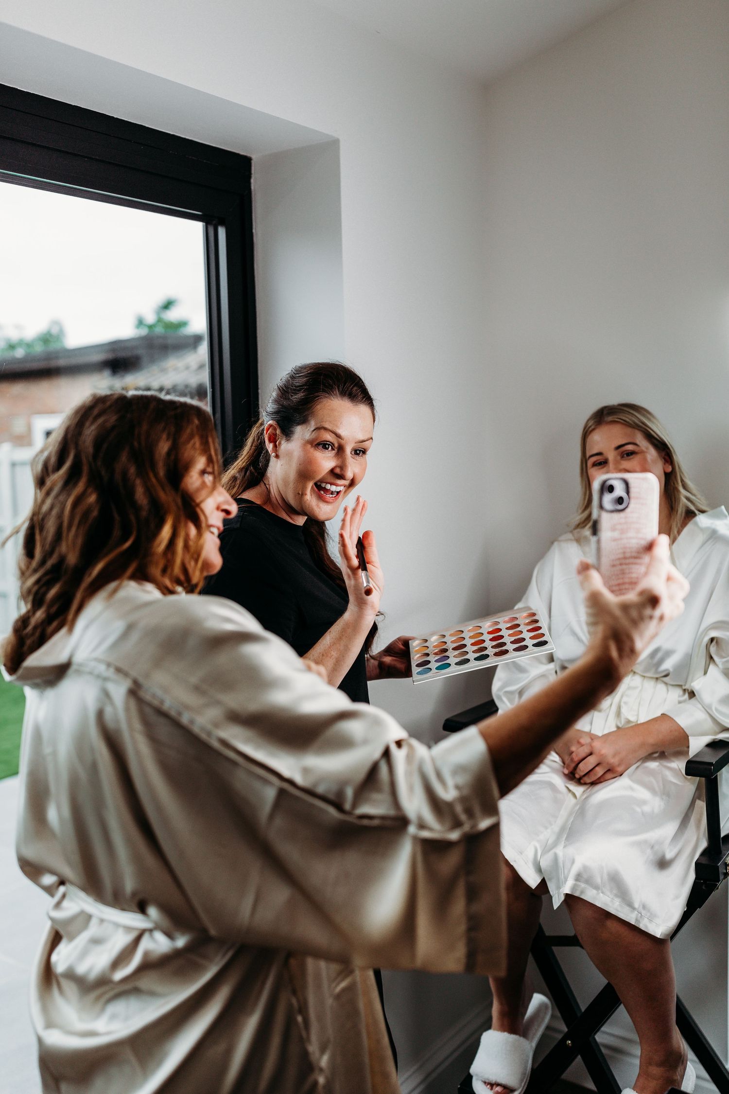 People sharing excited moments while getting ready in bright white room.