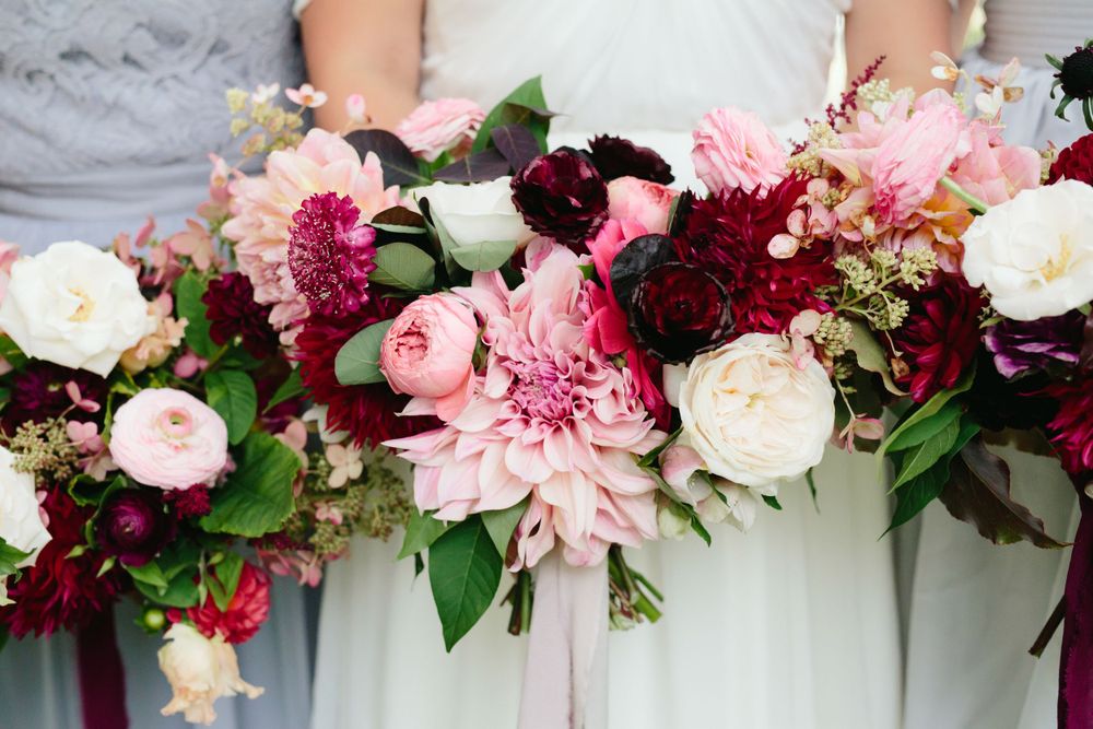 Lush bouquet featuring pink, burgundy, and white flowers with deep green foliage.