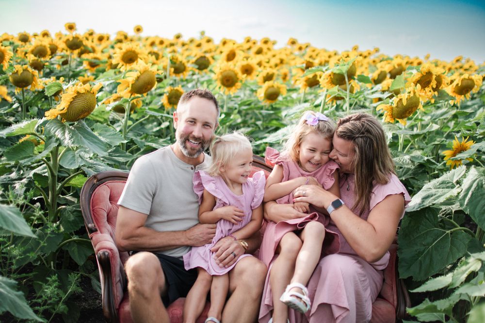 Family moments captured on a vintage pink couch surrounded by blooming sunflowers.