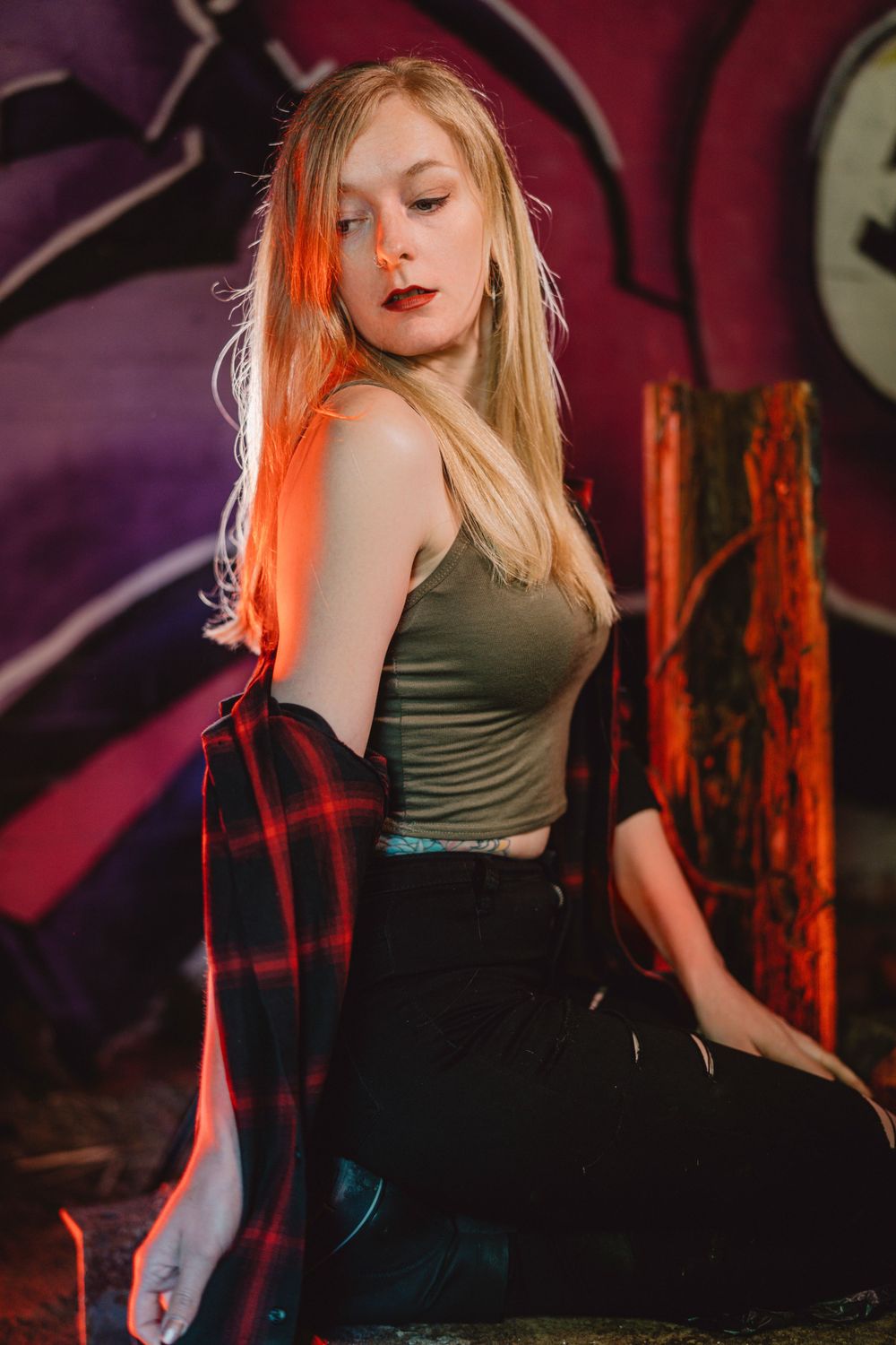 Dramatic dance poses in olive green top against purple-lit background.