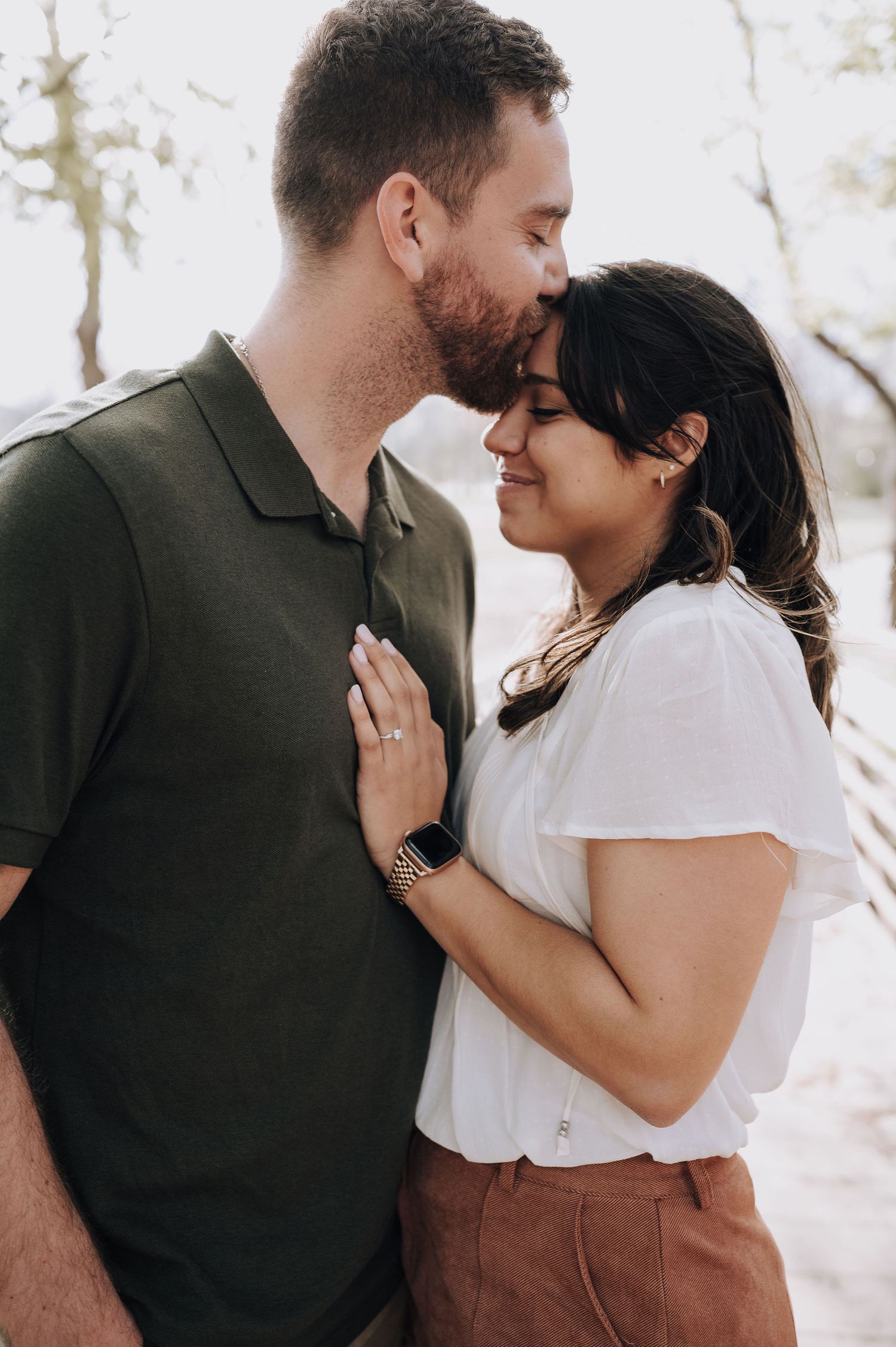 A tender moment between a couple in contrasting dark and light casual outfits.