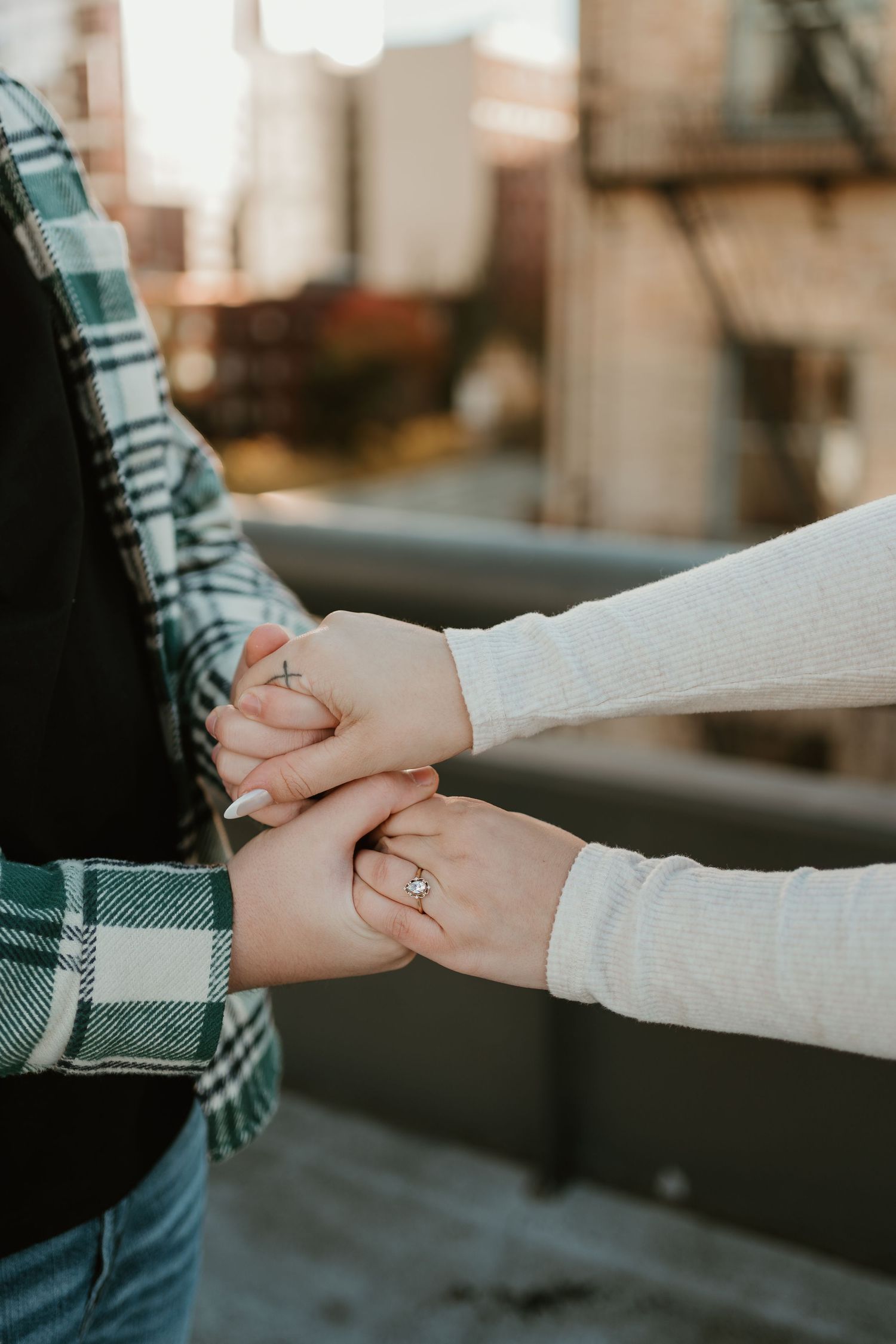 Close-up of hands holding each other with engagement ring visible.