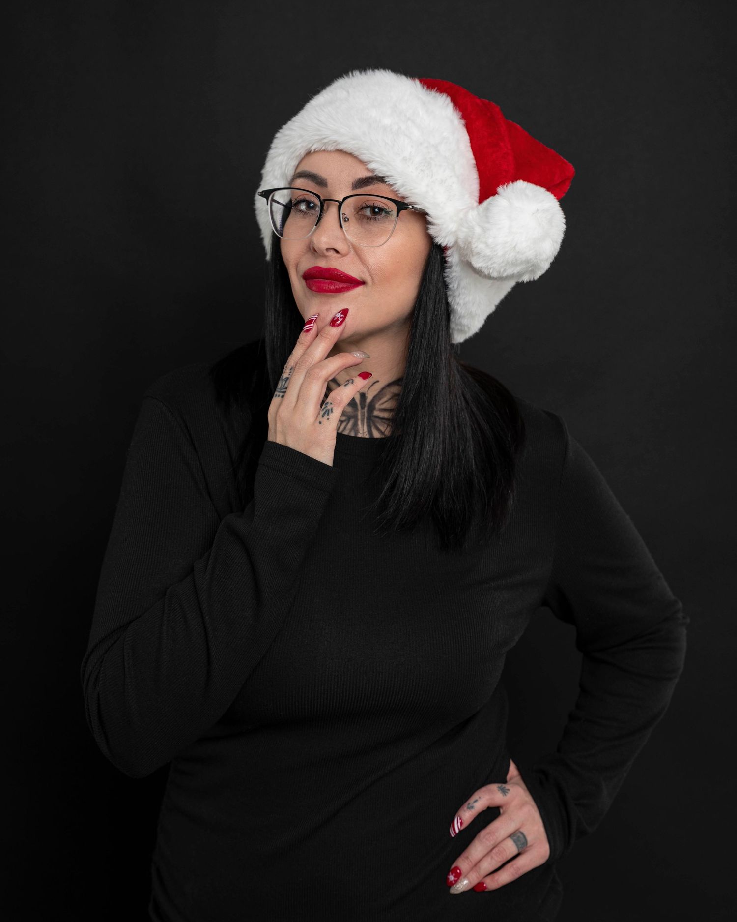 Person wearing Santa hat and black sweater poses against dark background.