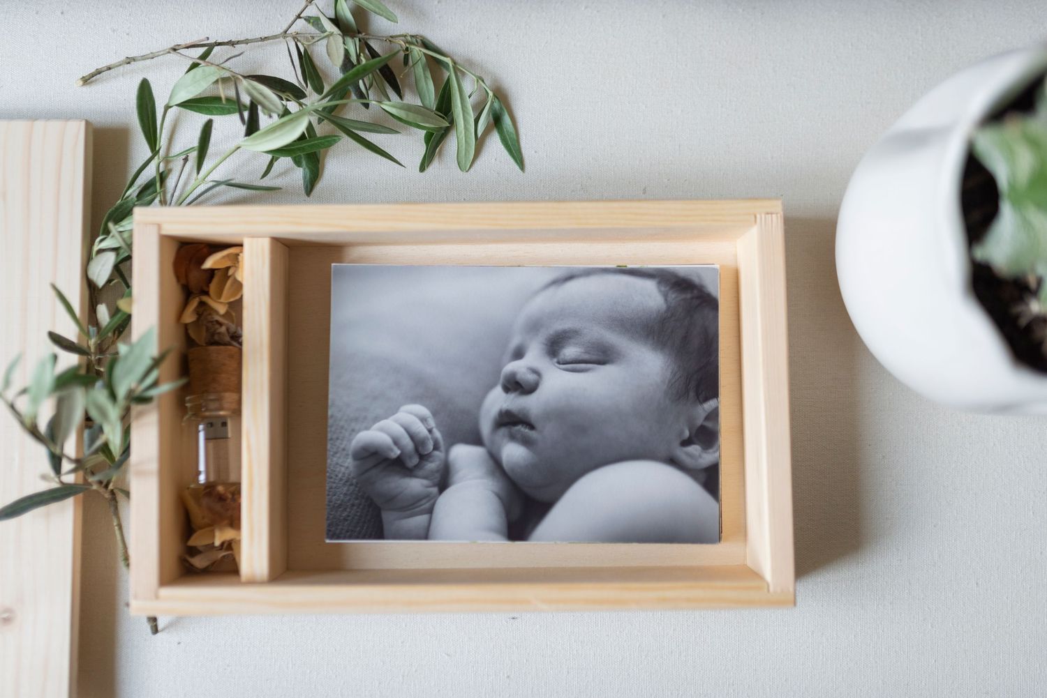 Black and white newborn baby photo in wooden frame with small glass vial.